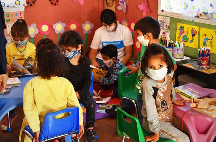 läsande barn i skola med munskydd mot färggranna väggar