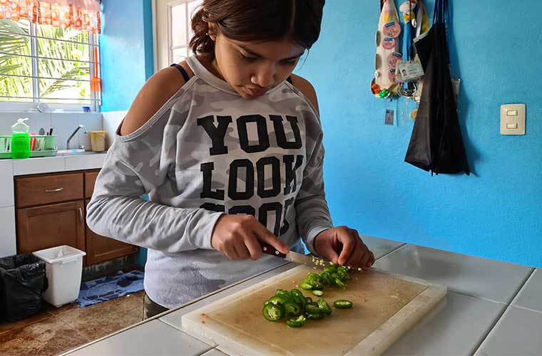 flicka i tröja med text hackar grön chili med kniv