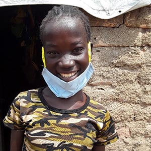 rassem ler med munskydd nere vid hakan i militärfärgad tröja med tegelvägg bakom