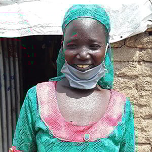 sya i grönrosa klänning ler står mot en tegelvägg