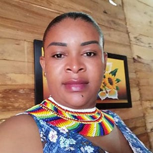 kvinna med färggrant halsband och blåblommigt linne med beslutsam blick