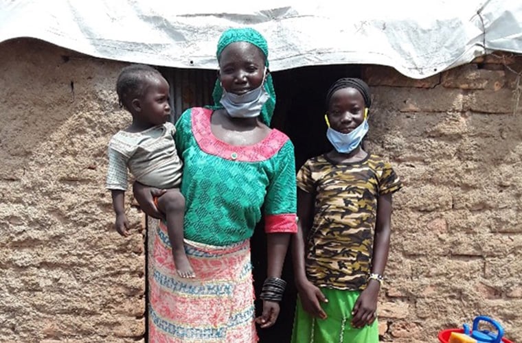 rassem och hennes mamma och lillasyster står med munskydd framför en tegelvägg