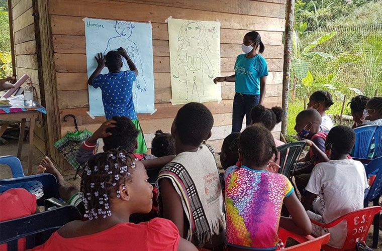 Redovisning framför publik där en man skriver på en affisch och en kvinna står bredvid 