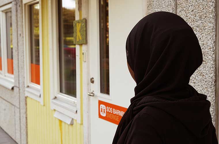 kvinna med svart sjal står framför sos barnbyars lokaler