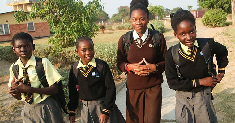 fyra flickor i skoluniform går på en väg