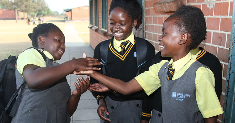 Flickor skojar och hälsar på varandra i skoluniform