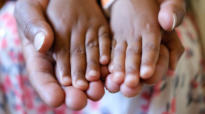 vuxenhänder som bär upp barnhänder